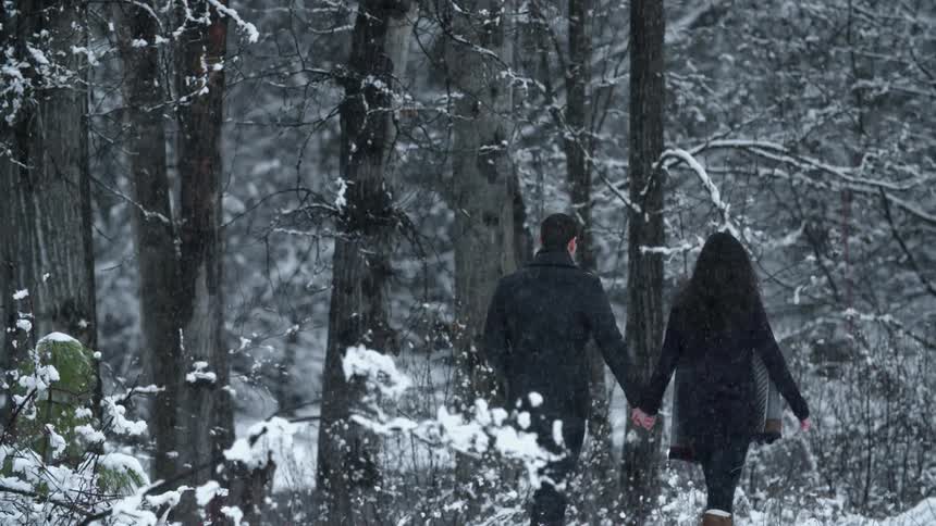 A man and woman holding hands during a walk on a snowy day