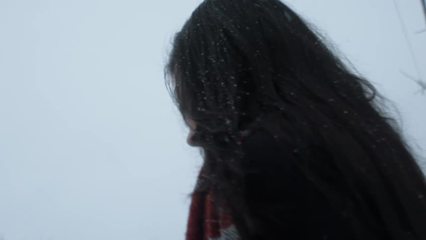 A man and women are walking outside as it snows
