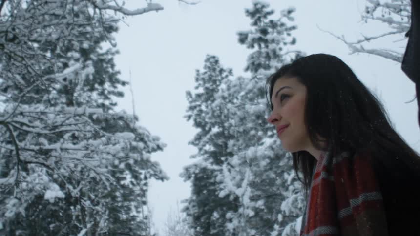 A man and woman walk outside while it snows