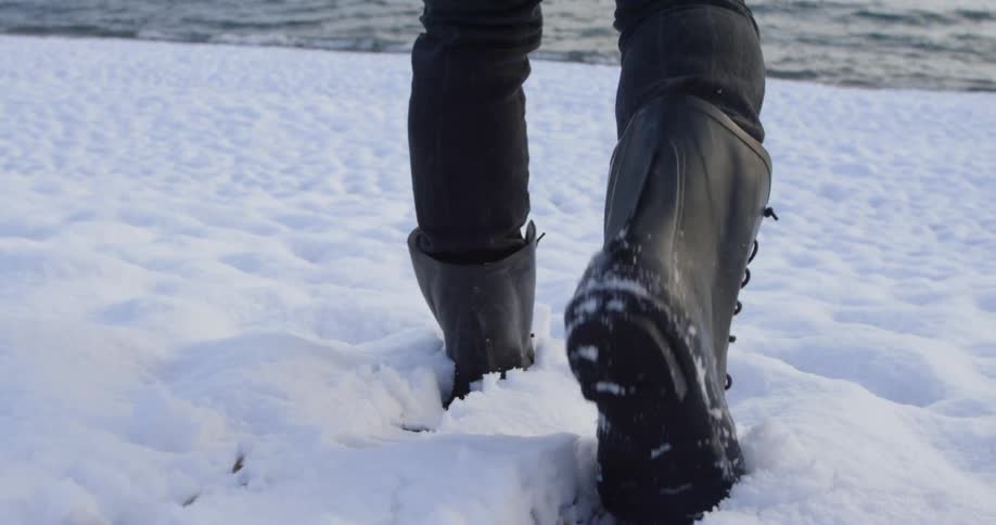 A man is walking across the snow