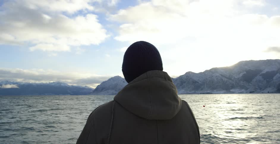 Man stands by the shore on a cloudy day