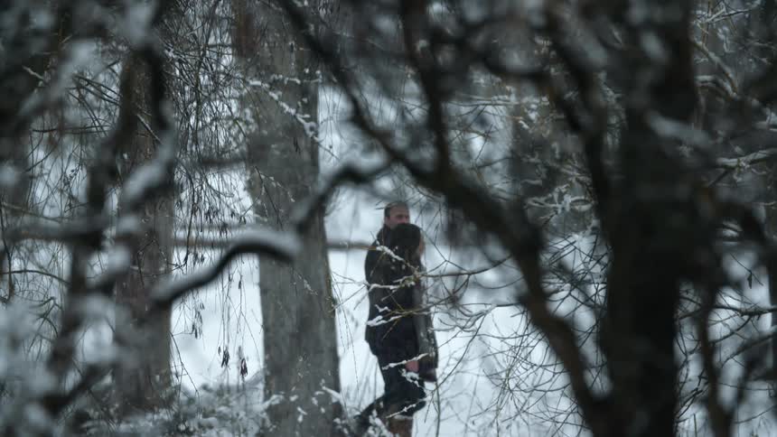 Man and woman walk through a snowy forest