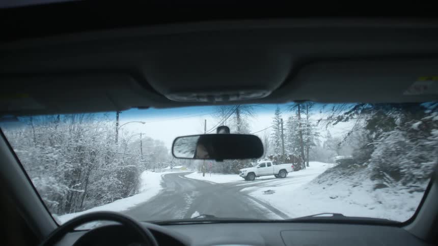 Person driving down a street surrounded by snow