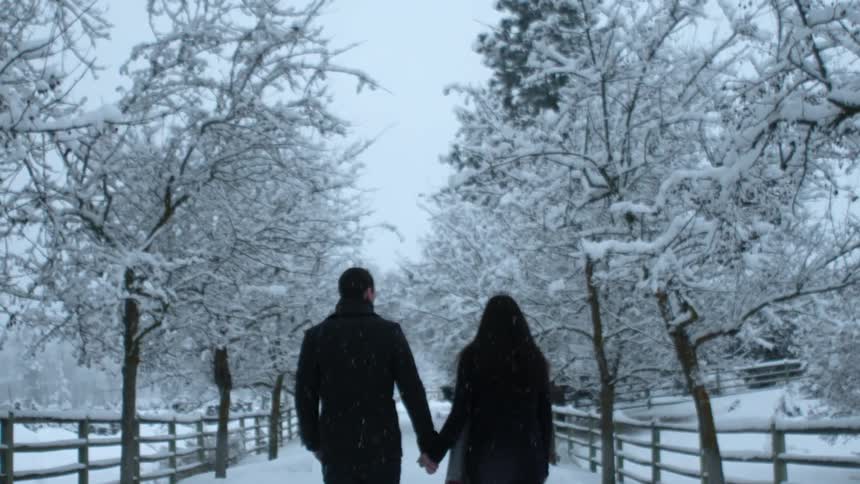 A man and women hold hands as they walk in the snow