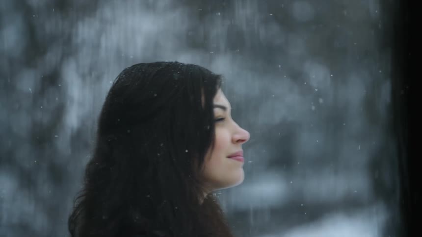 A woman stands smiling outside while it snows