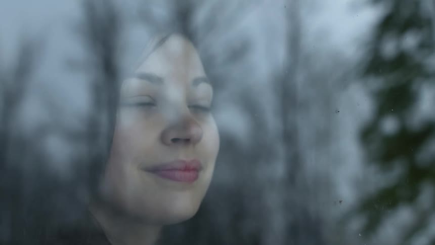 A woman smiles as she looks through the window