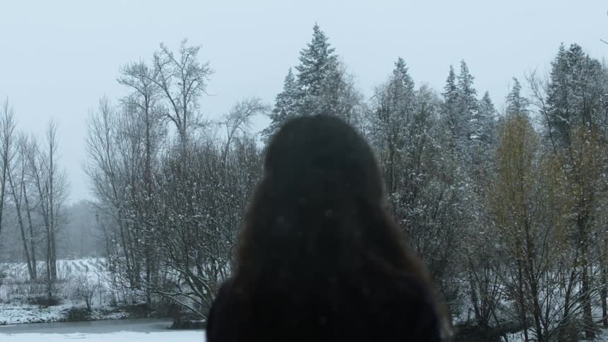 A woman standing outside while it is snowing