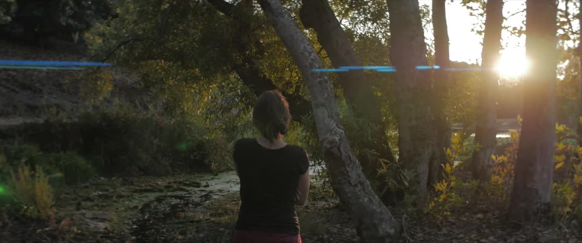 A woman stands in front of a group of trees