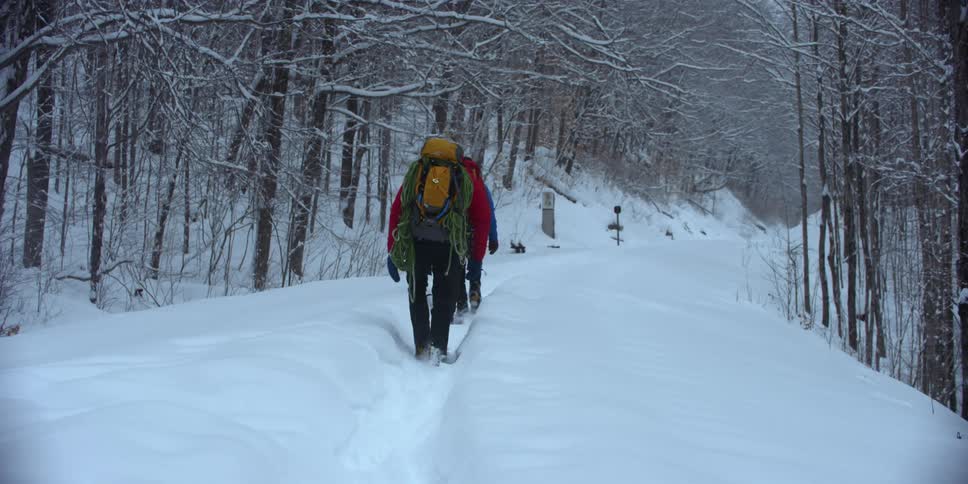 Hikers are trudging through a path covered with snow in winter