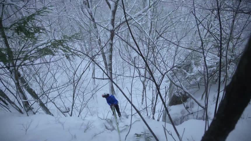 A frozen snow covered hillside with someone repelling down it