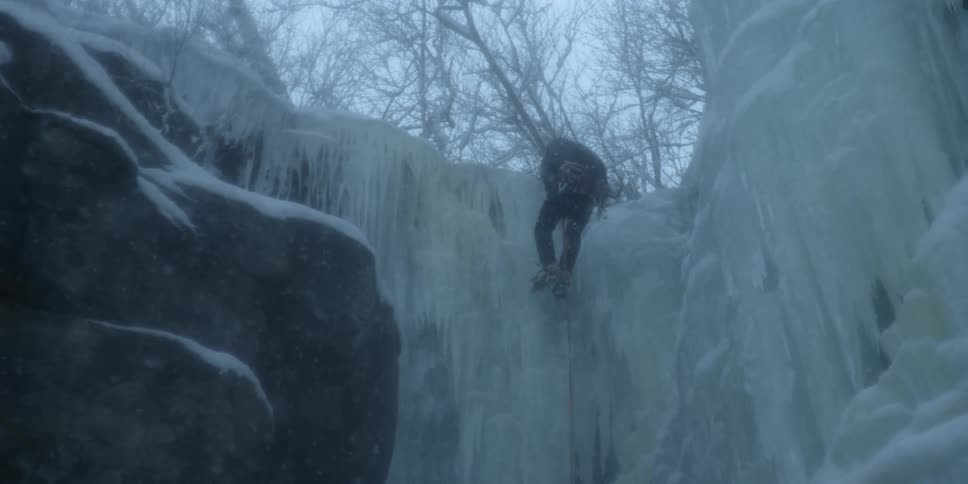 A man is climbing down a frozen waterfall