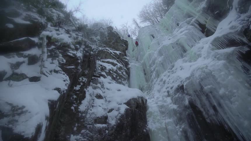 The snow falls fast by the tall cliff