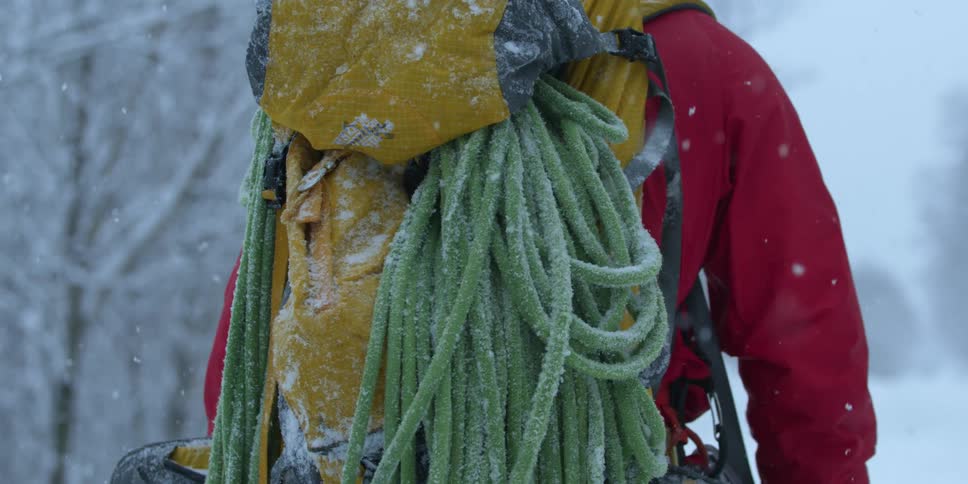 Snow is falling on hikers carrying climbing gear