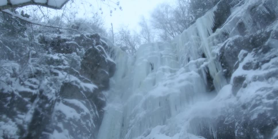 The snow is falling over the ice covered cliff