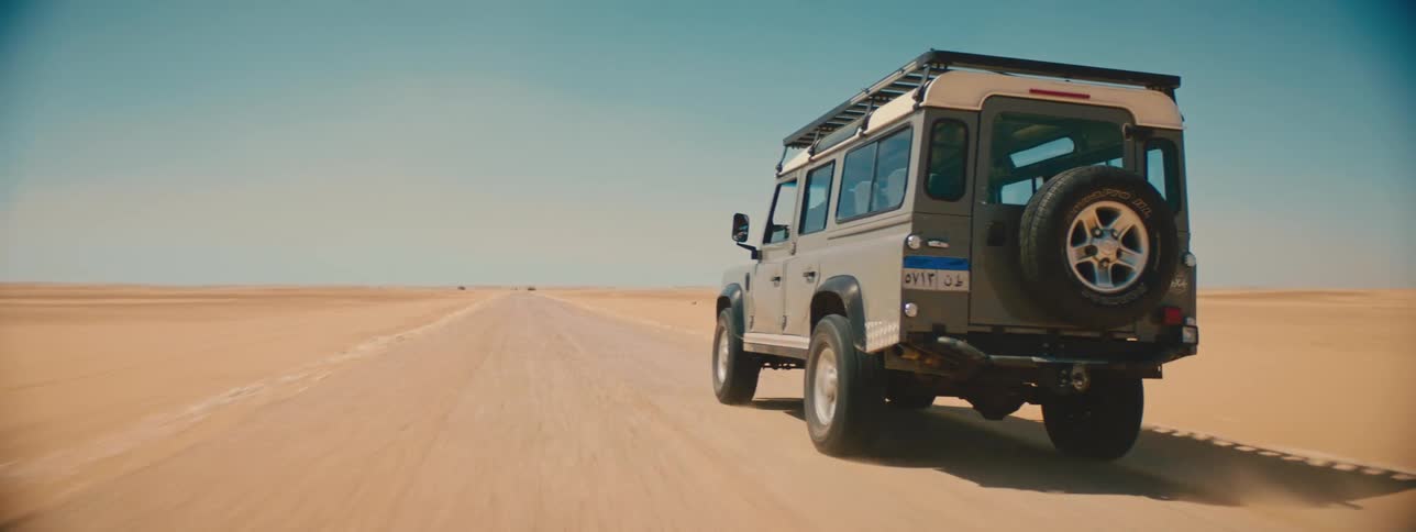 A man drives a sport utility vehicle through a desert