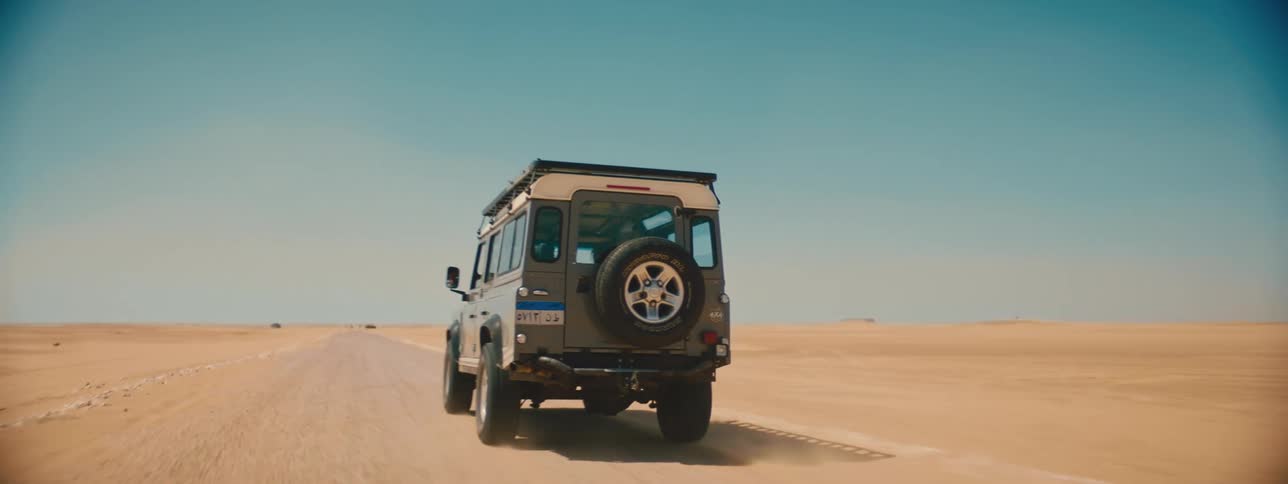 Jeep driving on a dirt road through the desert under the blue sky