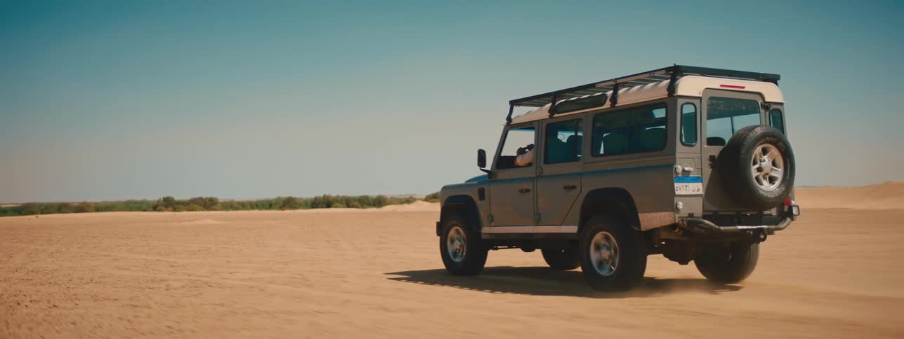 A person drives a vehicle offroad through the desert on a clear day