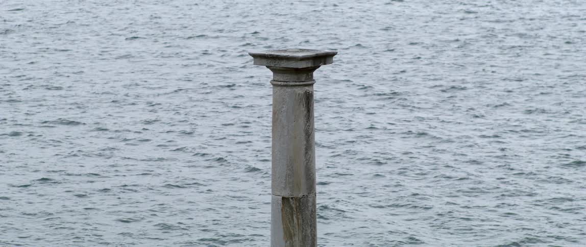 Concrete column in front of the calm surface of a lake