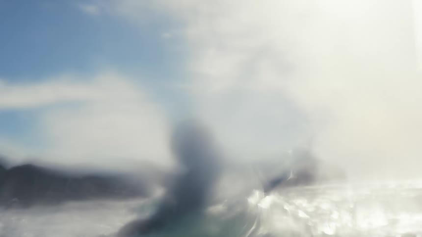 Young man wearing black wet suit swimming over a surfboard in the ocean