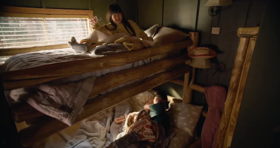 Woman with straight hair and gray sweatshirt wakes up son and daughter hitting door in haste