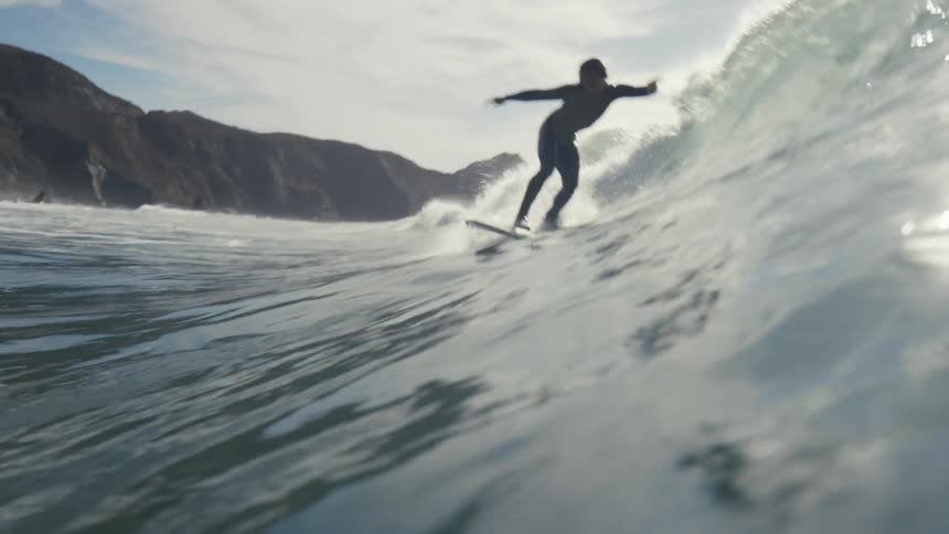 A surfer rides a wave that lands on the shore