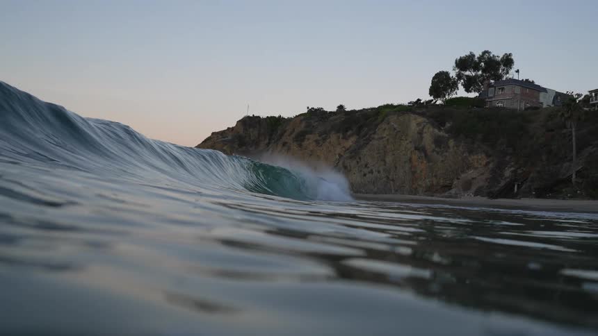 A wave approaches a beach in the evening as seen from in the water