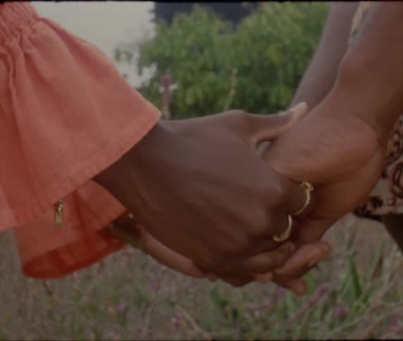 Two woman are holding hands while standing outdoors on a breezy day