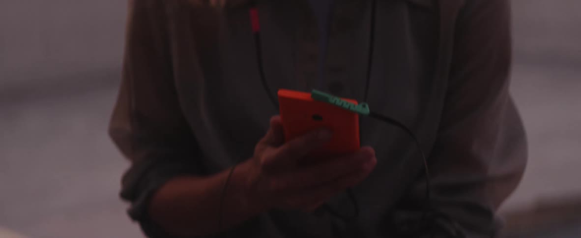 Hands hold up a smartphone with earphone jack plugged in