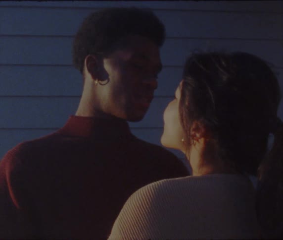 A man and woman are standing close and staring into one anothers eyes