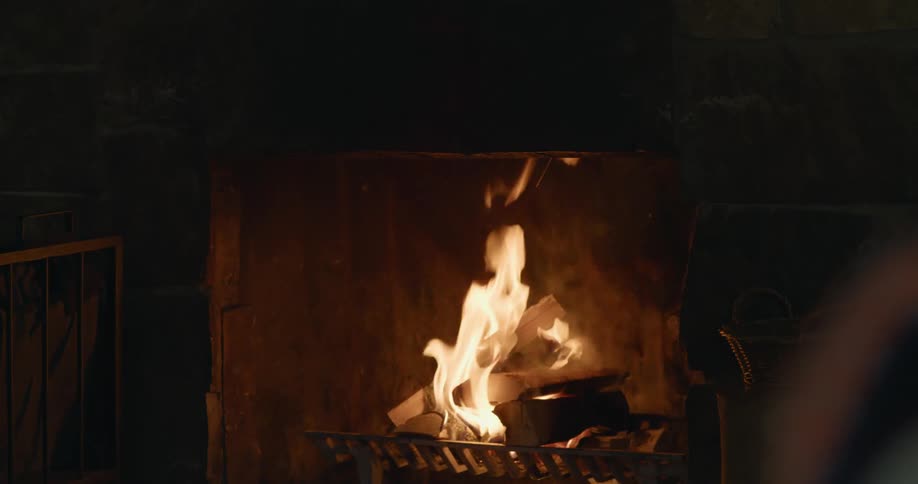 A fire burns in a fireplace in a rustic home