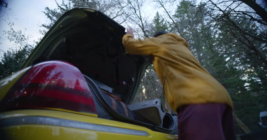 A man quickly loads luggage in the trunk of a taxi throwing some bags in