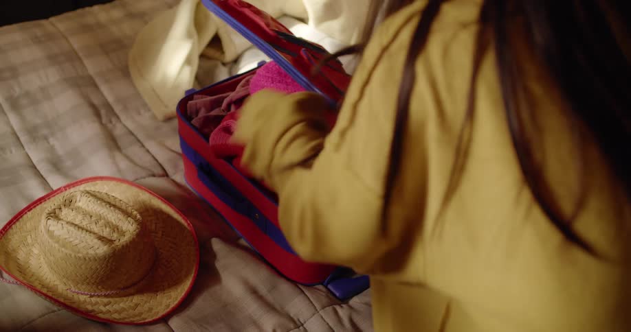 A woman packing a suitcase on a bed