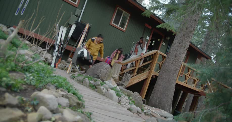 A family is rushing out of their home with luggage and suit cases