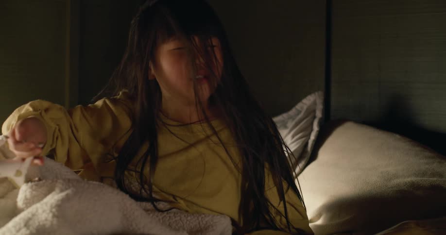 A little girl sits up in bed waking suddenly