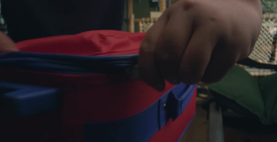 A person zipping up a suitcase in a room