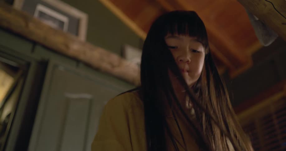 A girl grimaces a bit as she stuffs clothing into a suitcase