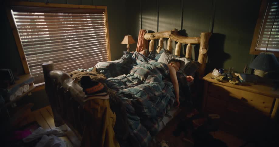 Couple sleeps in bed with rustic wooden log frame