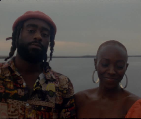 A man and woman posing together with the ocean behind them