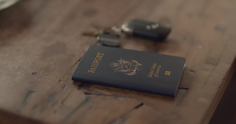 A passport and car keys are resting on a table until a man grabs them in the daytime