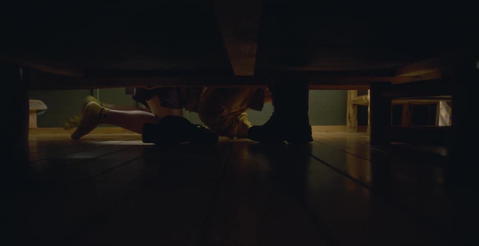Boy with shorts and white socks takes a pair of boots from under bed