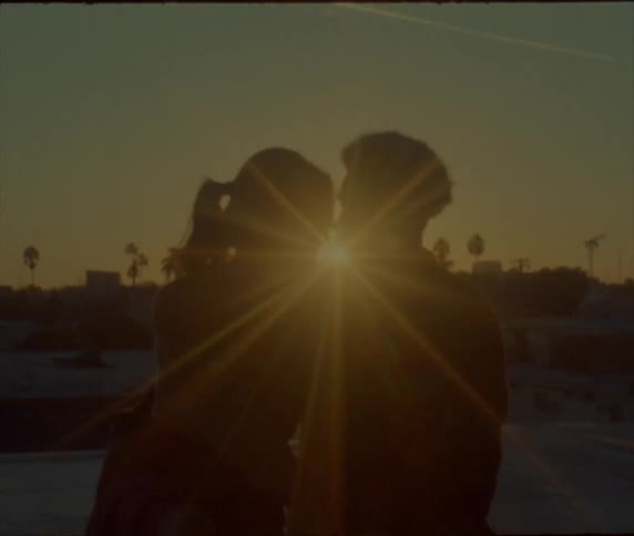 Back lighting from sun turns hugging couple into silhouettes