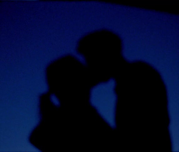The shadows of two people kissing can be seen in the dark