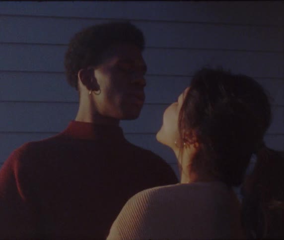 A boyfriend and girlfriend kissing outdoors