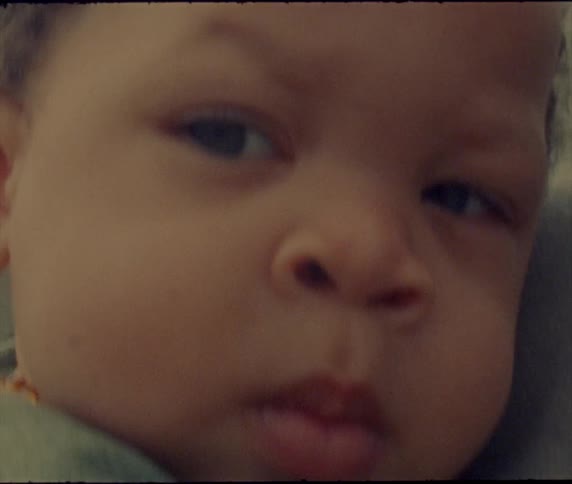 A baby is looking around and he looks unhappy