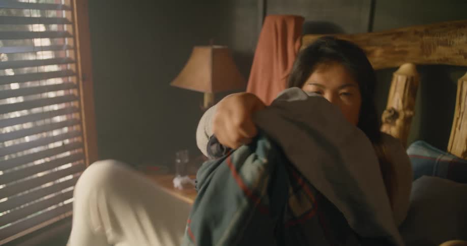 A woman sits up in bed and taps her husband to wake up before rushing out of bed