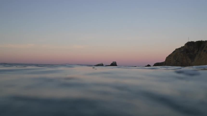 Sea wave moves across the surface of the sea at bay at dusk