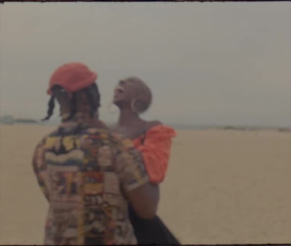 A man lifts a woman and spins her around while they stand in a desert on a cloudy day