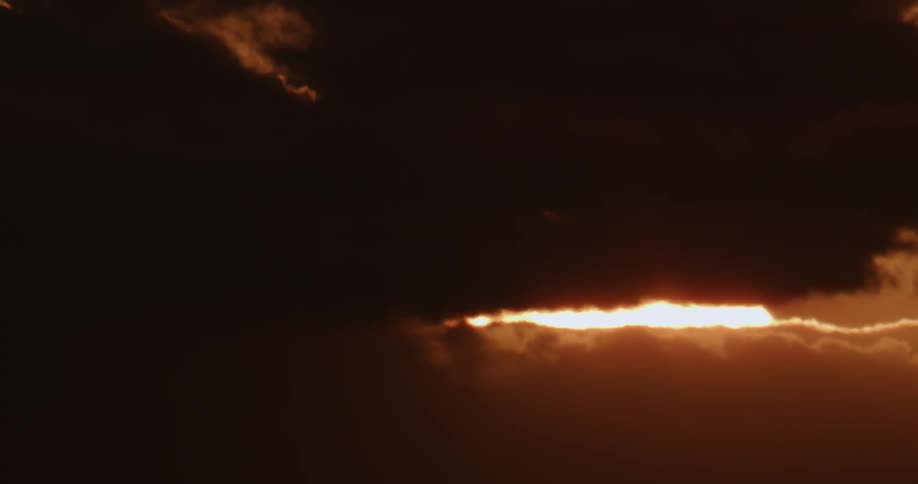 A view of the sun rising behind clouds