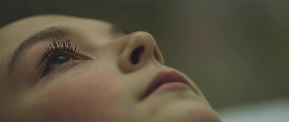 A woman lies on the ground and looks up at the sky