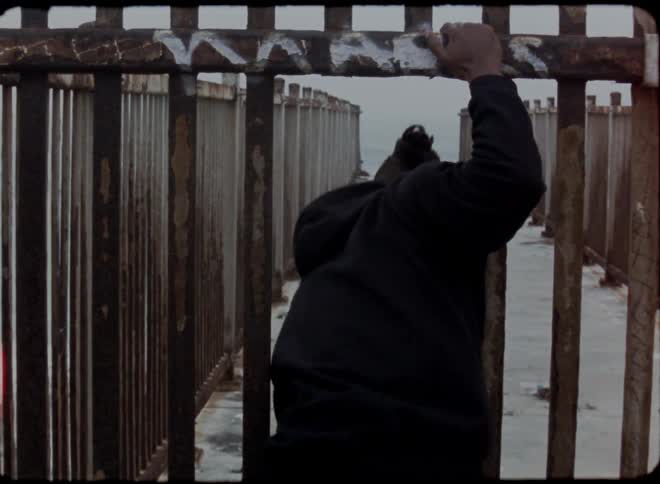 A man walks through the bars of a fence and on to a snow covered walkway